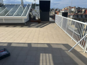 Terraza amplia con suelo de cerámica en tonos claros, con una vista de edificios cercanos