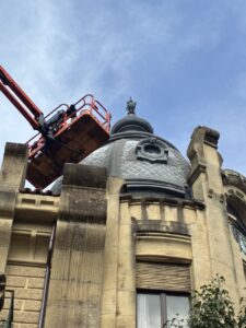 Techo de edificio con una estructura en altura y una grúa trabajando en la rehabilitación de la cúpula.