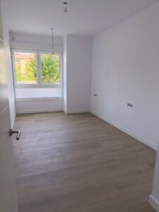 Habitación vacía con suelo de madera clara y ventanas grandes