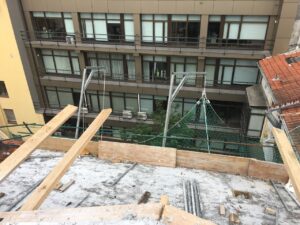 Vista de obras con estructuras de madera y red de seguridad en el edificio