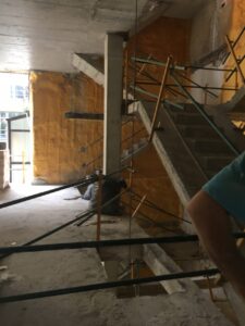 Escalera de edificio en reforma con andamios y paredes amarillas