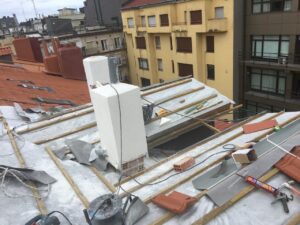 Techo parcialmente cubierto con tejas y materiales de construcción, vistas de edificios adyacentes