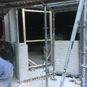 Pared en construcción con ladrillos blancos y andamio
