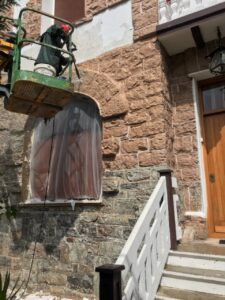 Fachada de vivienda en proceso de rehabilitación con andamiaje y trabajador.