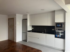 Cocina con mobiliario blanco, encimera negra y electrodomésticos de acero inoxidable