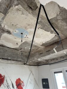 Techo deteriorado con cables visibles y pintura en pared blanca