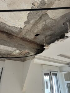 Techo con daños visibles y áreas en reparación en un interior residencial