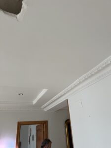 Techo de una habitación con moldura decorativa y un espacio dañado