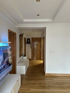 Pasillo amplio con paredes blancas y suelo de madera, mobiliario minimalista