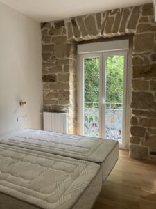 Habitación con dos camas individuales y pared de piedra natural