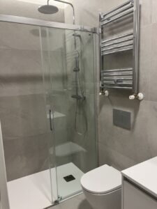 Ducha con cerramiento de cristal y detalles en acero inoxidable en un baño