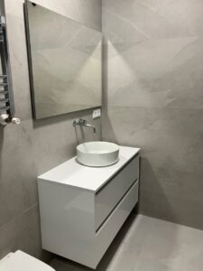 Mueble de baño moderno con lavabo montado y espejo en pared gris