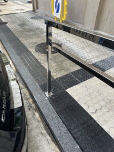 Barandilla de acero inoxidable instalada en la acera con adoquines y textura antideslizante