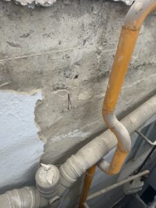 Tuberías de PVC y metal en una pared con revestimiento desgastado
