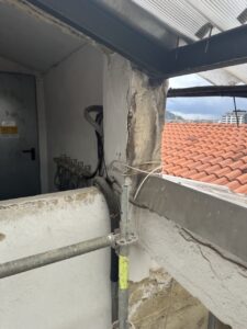 Esquina de una estructura en proceso de rehabilitación con grúas y tuberías visibles