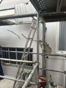 Escalera apoyada en andamios junto a paredes en proceso de rehabilitación