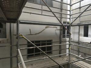 Andamiaje en un proyecto de rehabilitación con paredes blancas y ventana visible