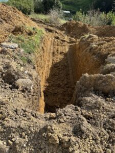 Zanja excavada en terreno con huellas de maquinaria pesada