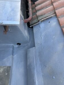 Cubierta detallada con acabados en gris y tejas rojas en un proyecto de rehabilitación