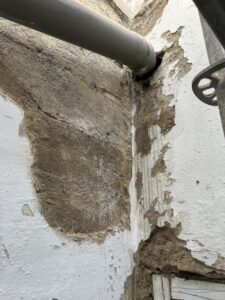 Pared en proceso de rehabilitación, con tubería visible y deterioro en las superficies