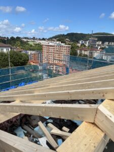 Estructura de madera en el techo de una obra con vista urbana al fondo