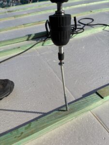 Taladro eléctrico realizando perforaciones en una tabla de madera verde