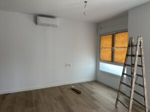 Escalera de aluminio junto a ventana con persianas naranjas en habitación