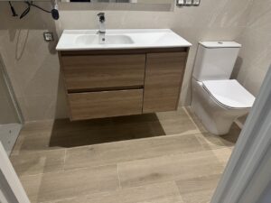 Baño reformado que muestra un mueble de madera, lavabo y sanitario