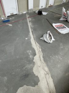 Suelo de obra con una grieta visible y materiales de construcción alrededor