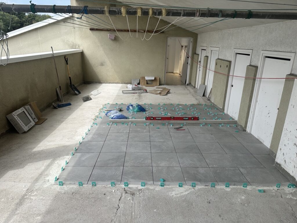 Suelo de cerámica en proceso de instalación con herramientas y materiales alrededor