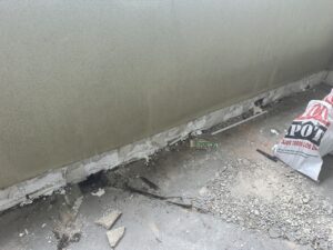Zona de obra con pared en proceso de rehabilitación y material de construcción en el suelo