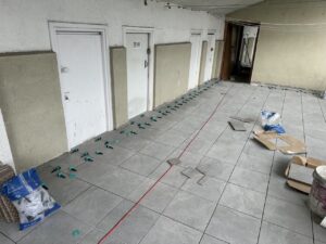 Espacio con suelo de cerámica en proceso de instalación, con piezas y herramientas visibles