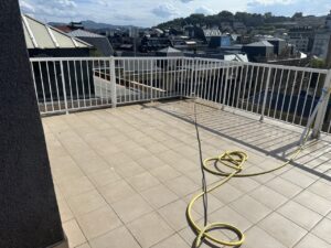 Terraza amplia con barandilla blanca y manguera amarilla en el suelo