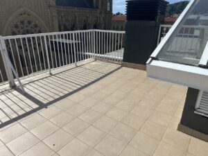 Terraza con azulejos claros y barandilla blanca, vista exterior de un edificio
