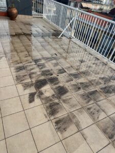 Terraza con baldosas sucias y manchas oscuras en el suelo