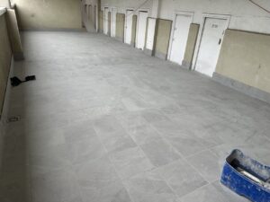 Suelo de cerámica gris claro en un espacio de obra con puertas en la pared