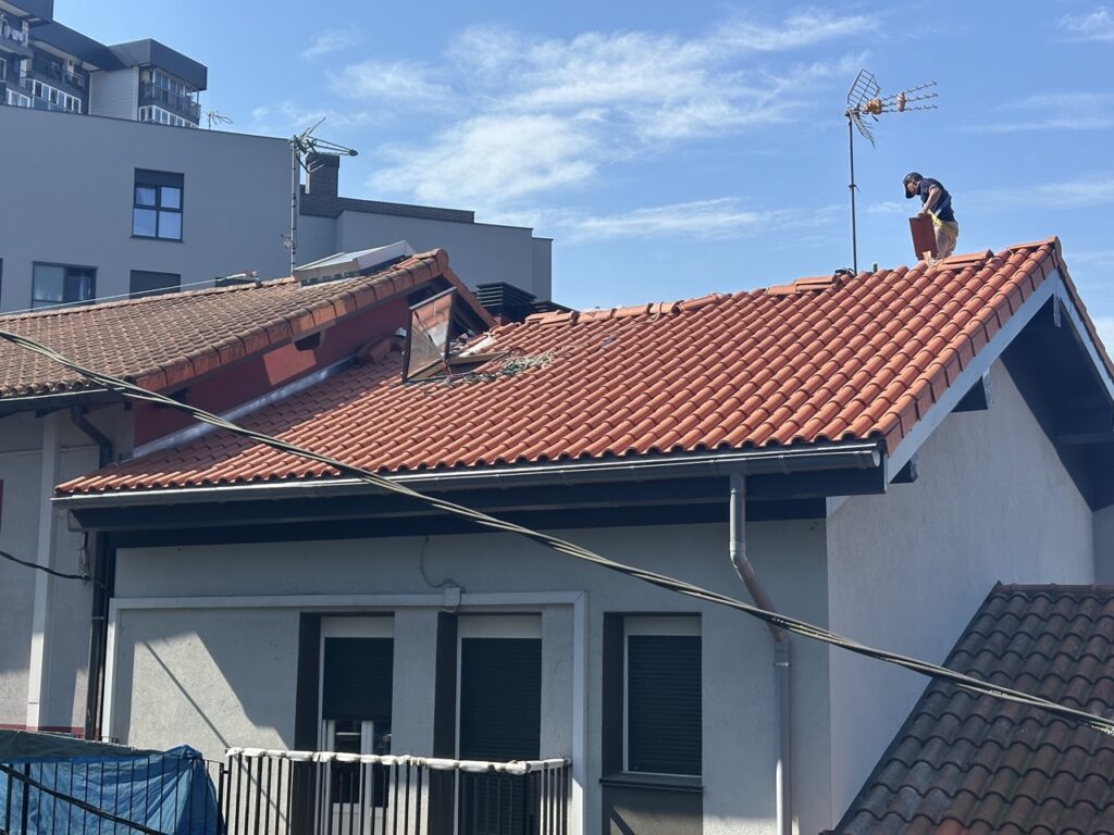 Hombre sobre un tejado con tejas rojas realizando trabajos de rehabilitación