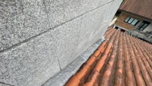 Cubierta de tejas rojas en proceso de rehabilitación con material gris en el borde