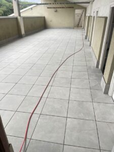 Suelo de cerámica gris claro instalado en terraza con cable rojo en el suelo