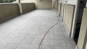 Terraza con suelo de baldosas grises y una manguera de obra