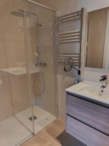 Ducha de vidrio en baño con lavabo y mueble de madera