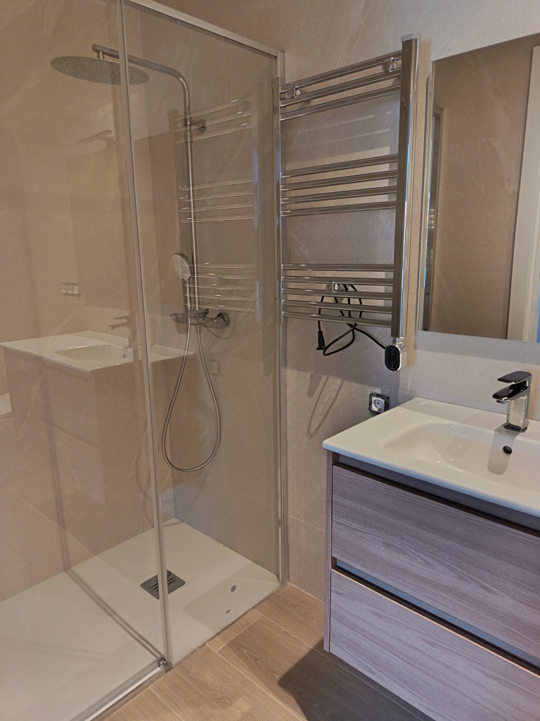 Baño moderno con ducha, lavabo y grifería en tonos neutros