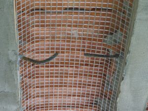 Rejilla de acero colocada sobre ladrillos expuestos en una obra