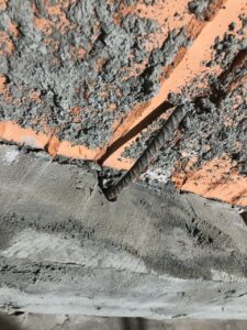 Muro de obra con cemento fresco y varilla de refuerzo expuesta