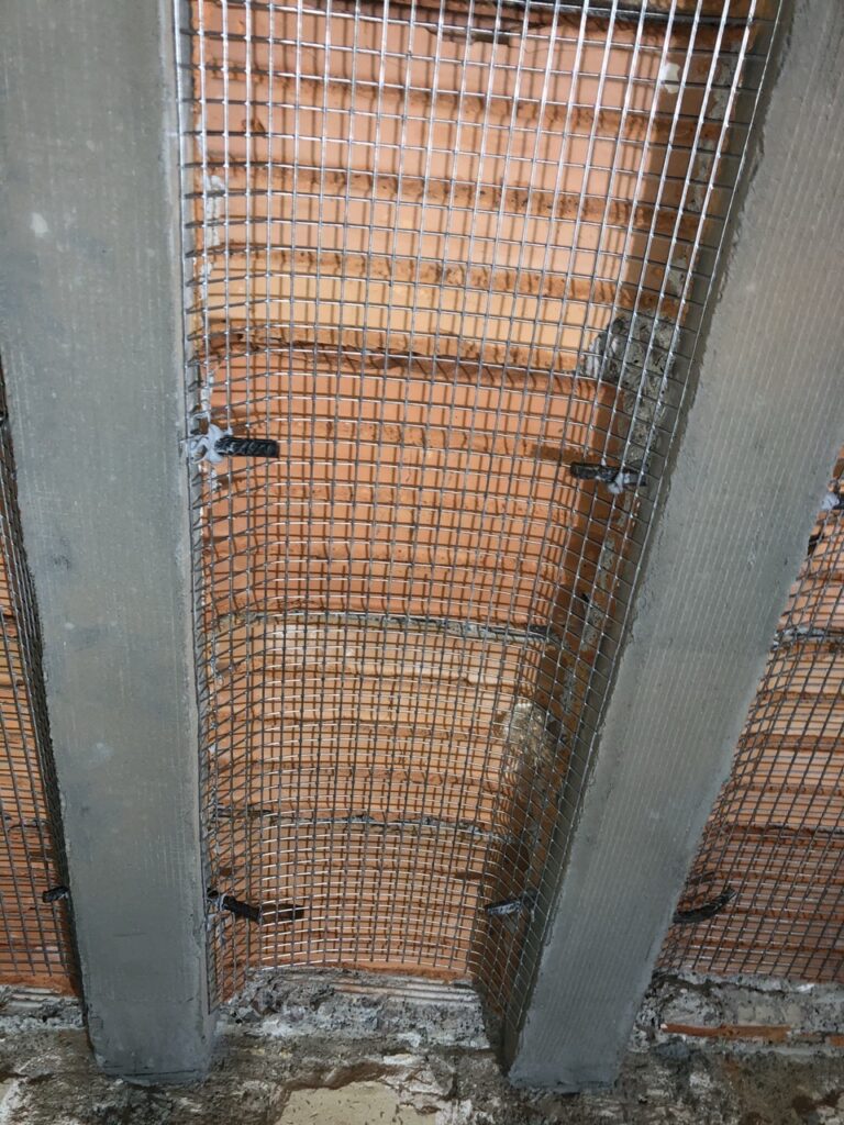 Malla de refuerzo metálica instalada en una pared de ladrillo