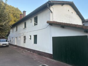 Fachada de una casa reformada de color blanco con garaje verde
