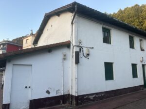 Fachada de una vivienda con paredes blancas y ventanas verdes