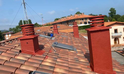 Tejado con chimeneas de ladrillo rojo y paneles solares