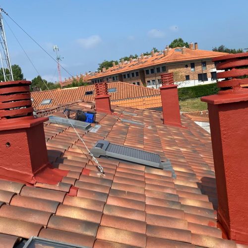 Tejado con chimeneas de ladrillo rojo y paneles solares