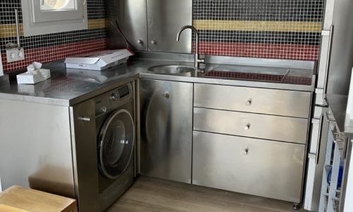 Cocina con muebles de acero inoxidable y azulejos coloridos en las paredes